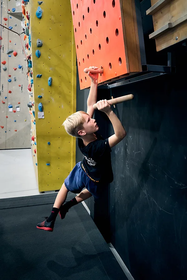 Junge klettert mit Stöcken hoch